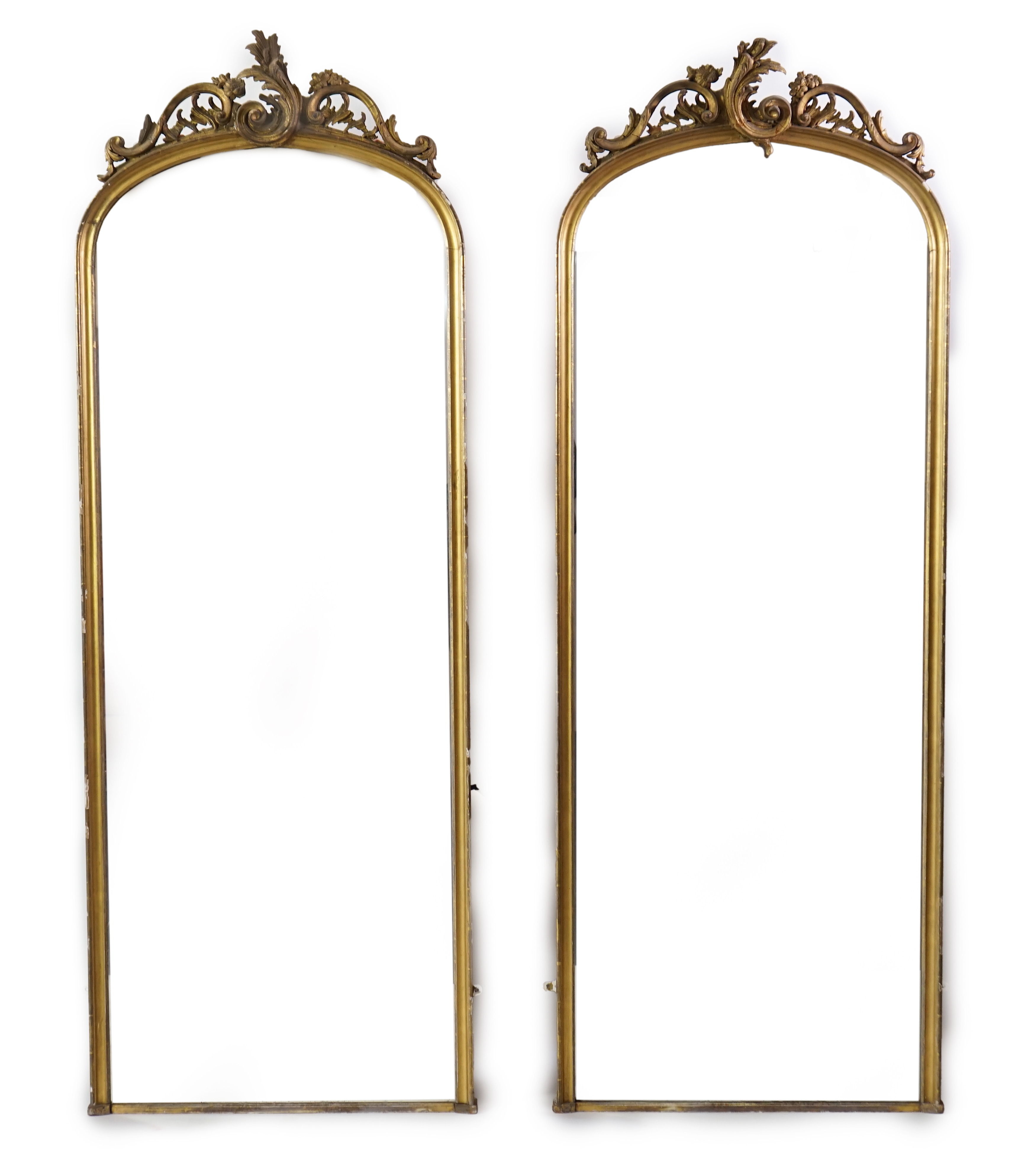 A pair of late 19th century giltwood and gesso pier glasses, with asymmetrical rococo scroll crests and arched plates, 80cm wide, 221cm high. Condition - fair